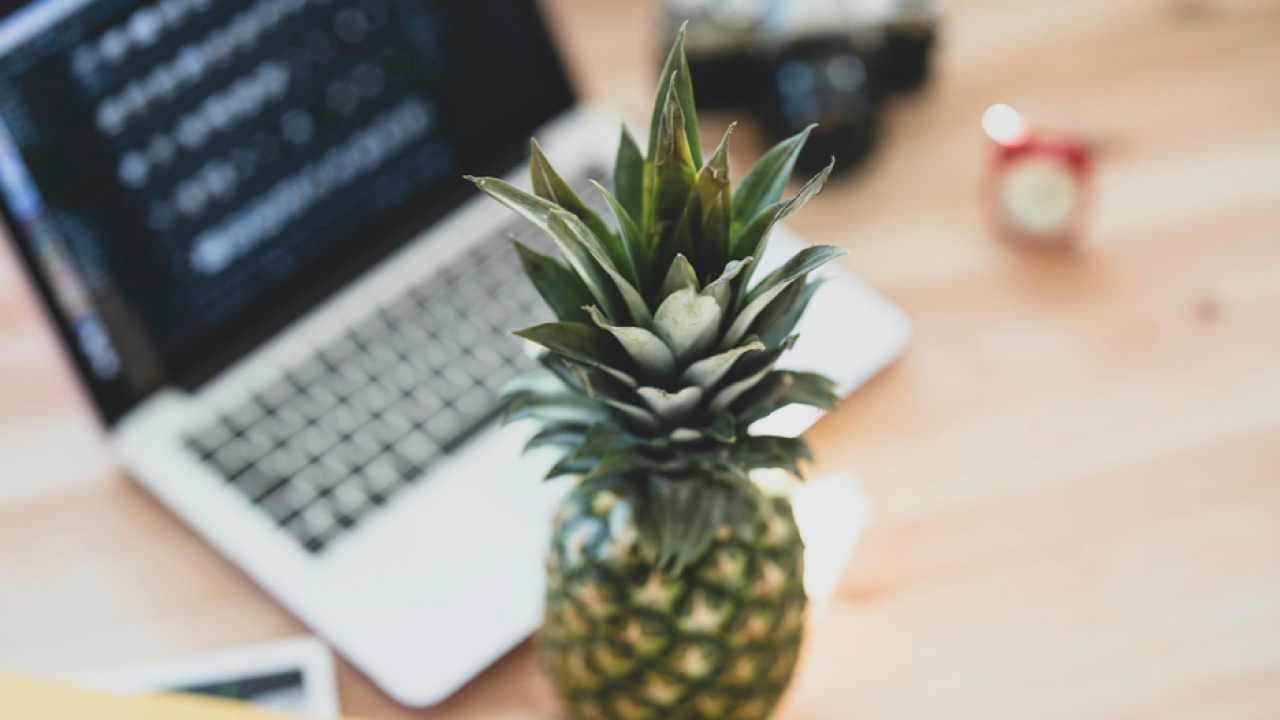 Pineapple next to computer on table