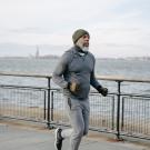 Black man running in NYC, Statue of Liberty and ocean in the background.