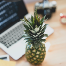 Pineapple next to computer on table